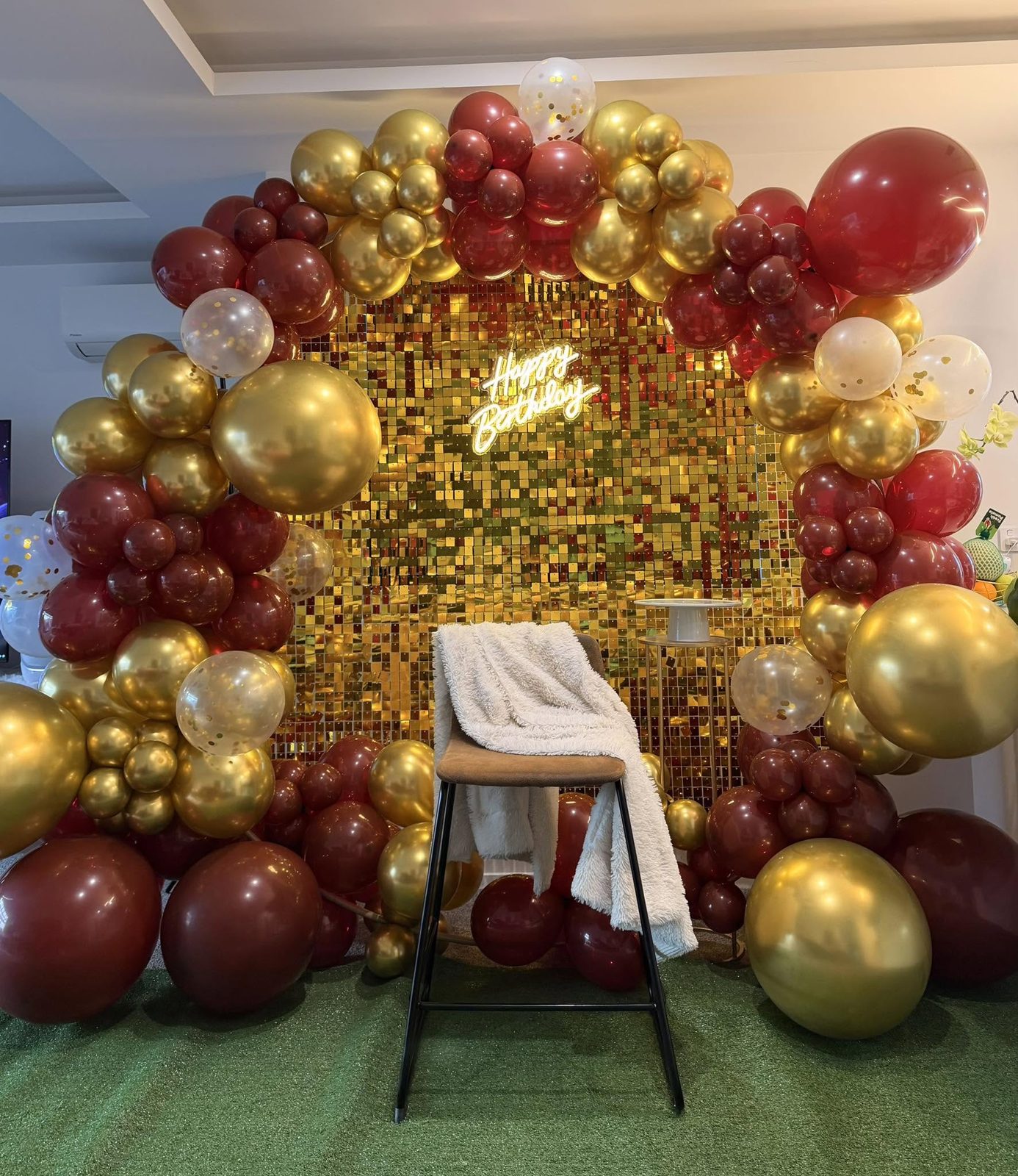 Burgundy and gold balloon ring around a sequin wall with a neon Happy Birthday sign
