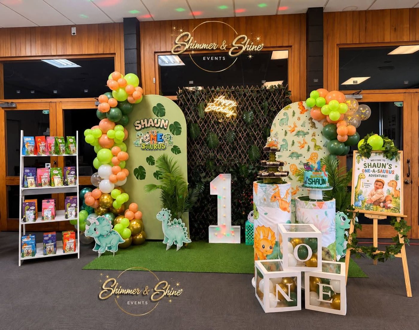 Dinosaur-themed first birthday with arches, balloon garlands, a giant number one and a cake table